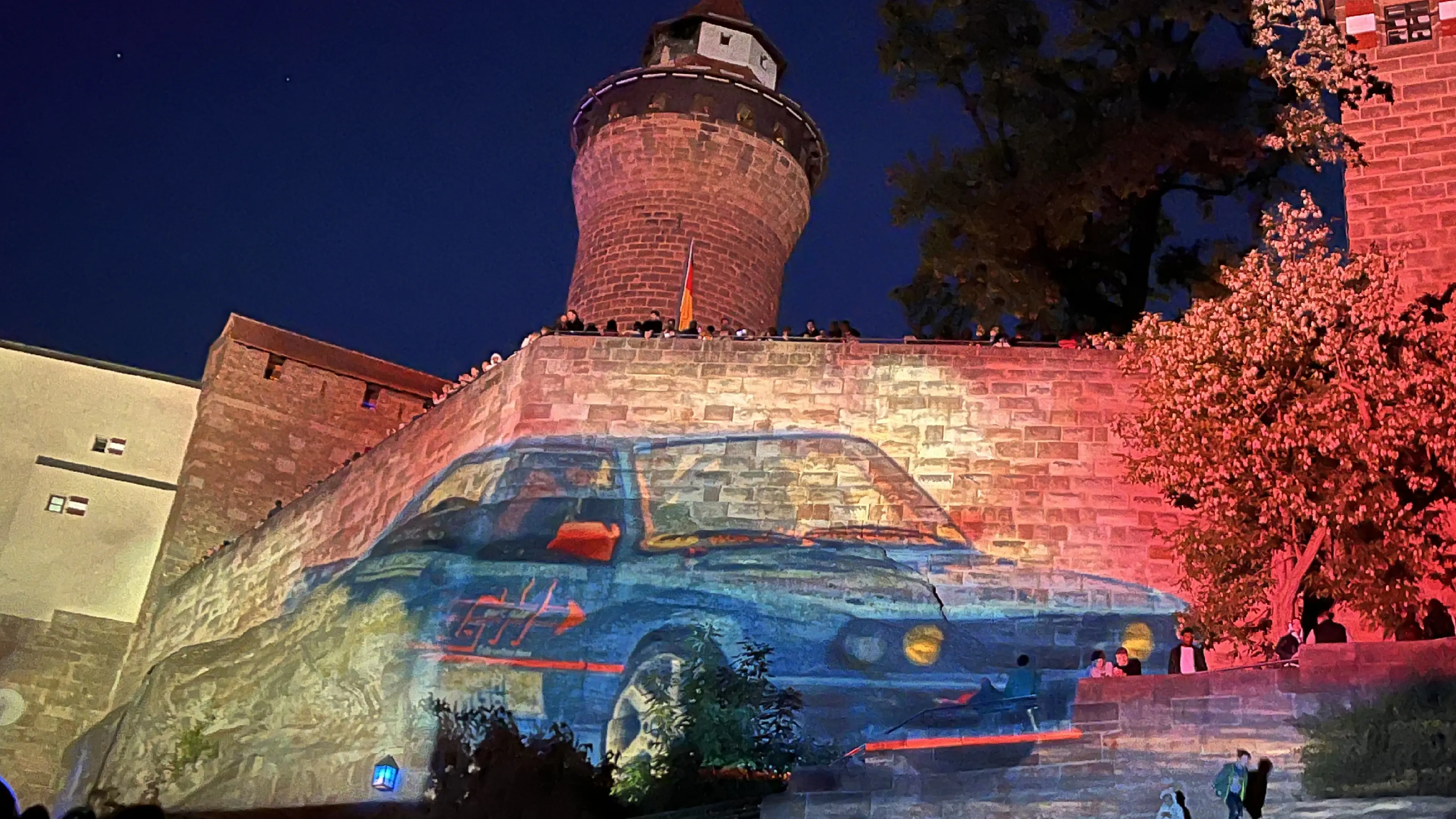Bei der Blauen Nacht Nürnberg 2025 wird ein blaues Rennauto auf die Kaiserburg projiziert