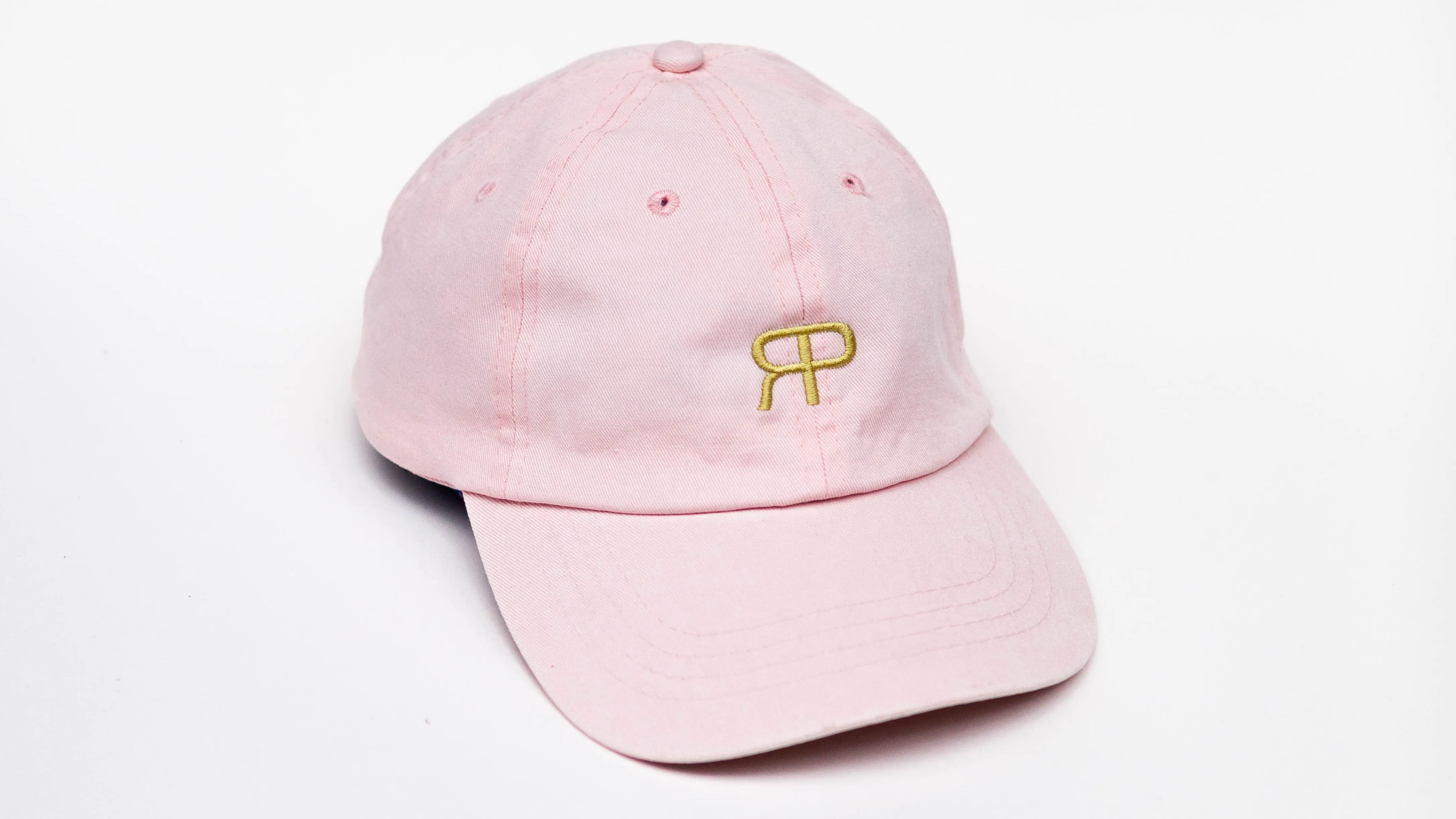 rosa Merch Cap mit gold besticktem Rose Pistola Logo vor weißem Hintergrund